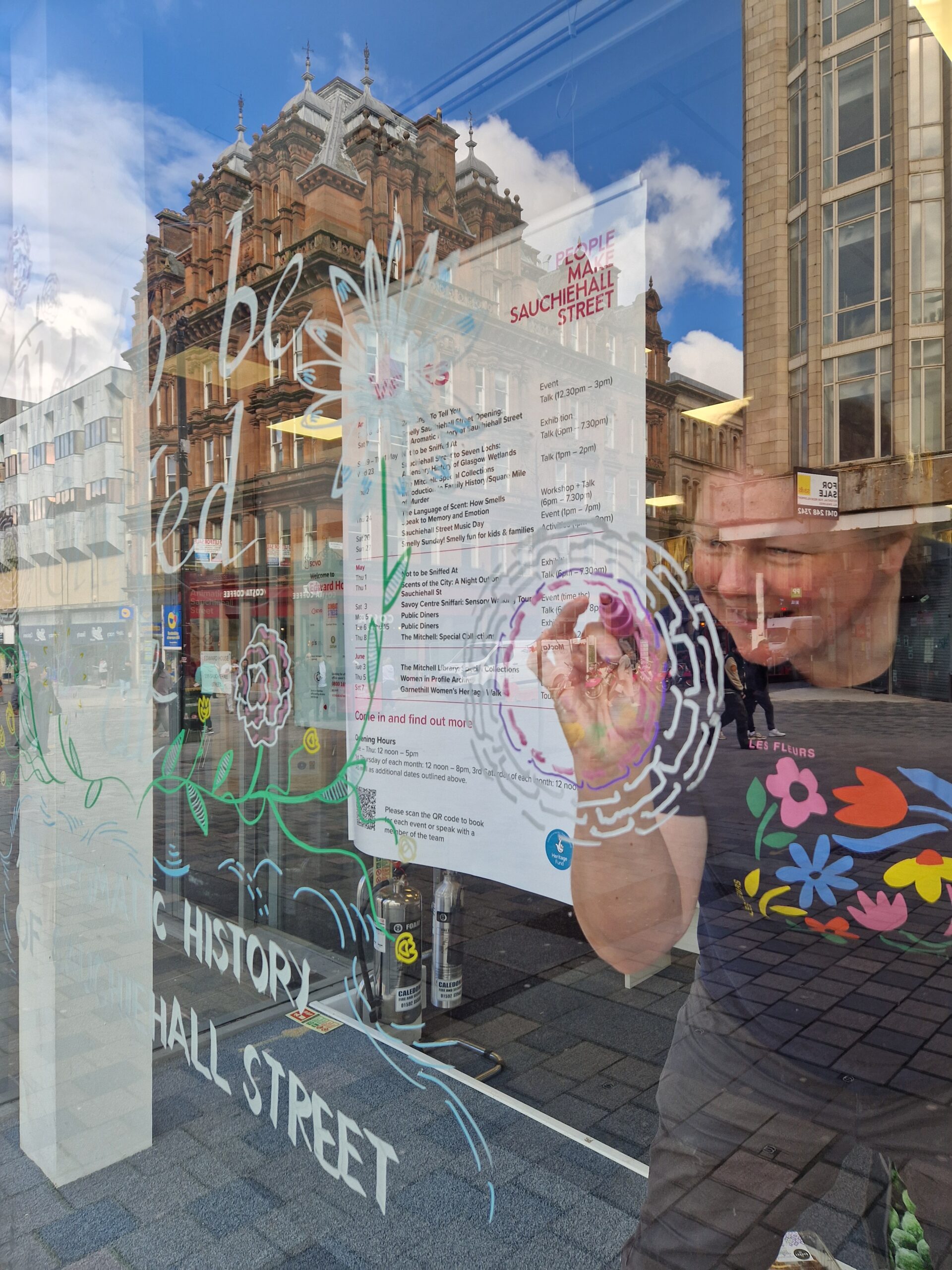A woman writing and drawing on a glass window.