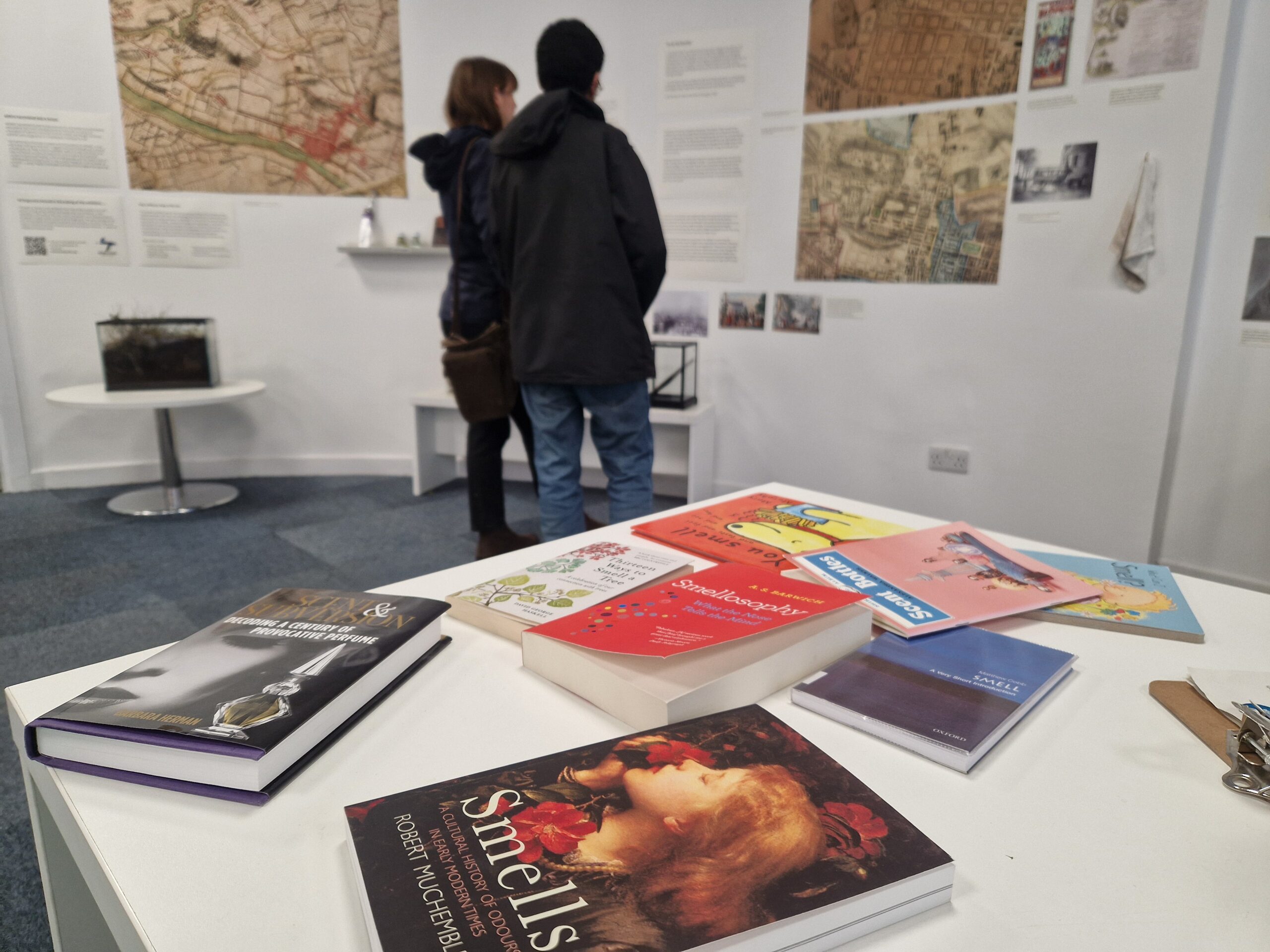 Books on a table with people in the background.