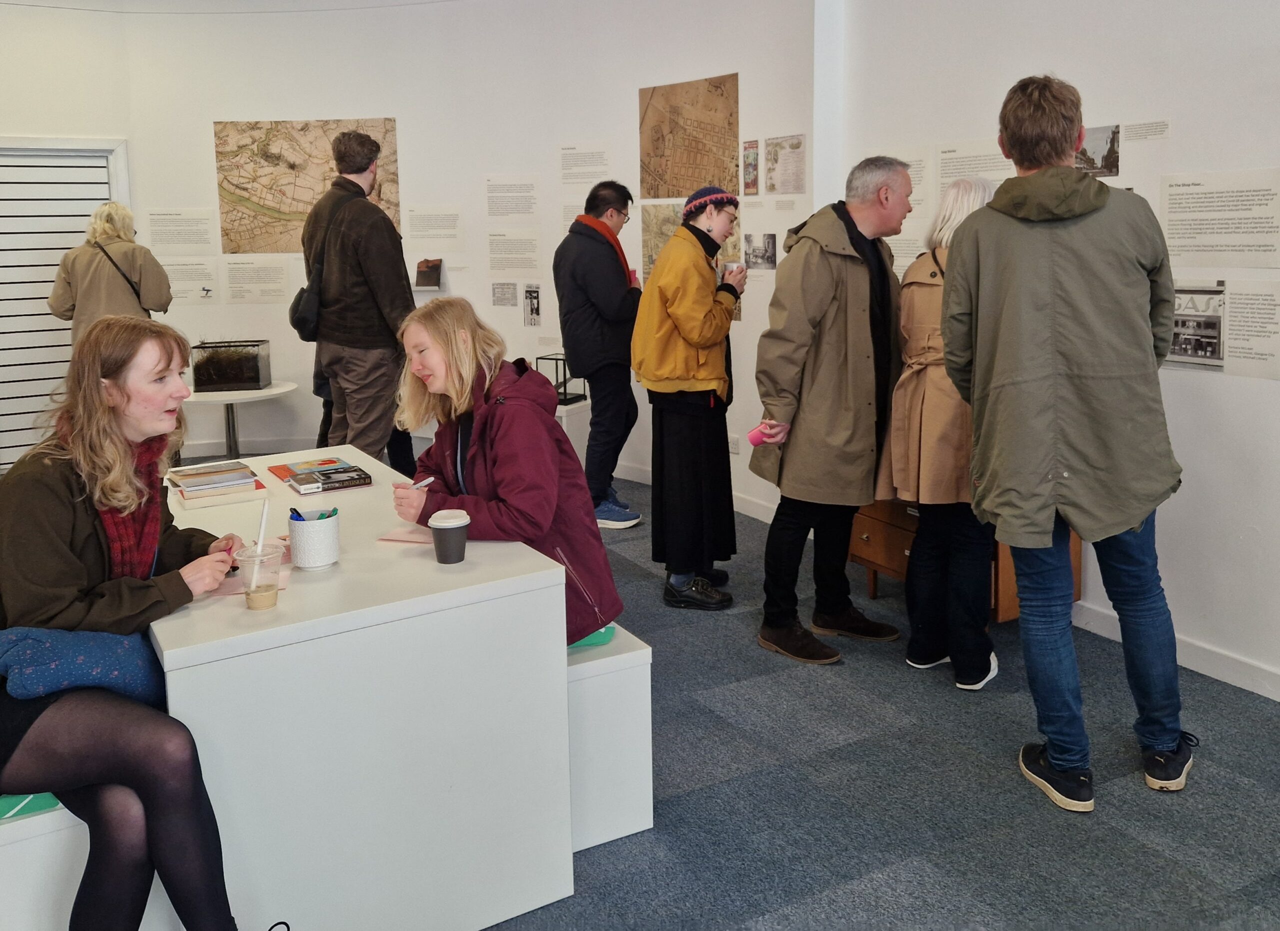 People reading text and looking at pictures at an exhibition.