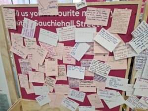 A pink noticeboard with lots of handwritten notes attached.