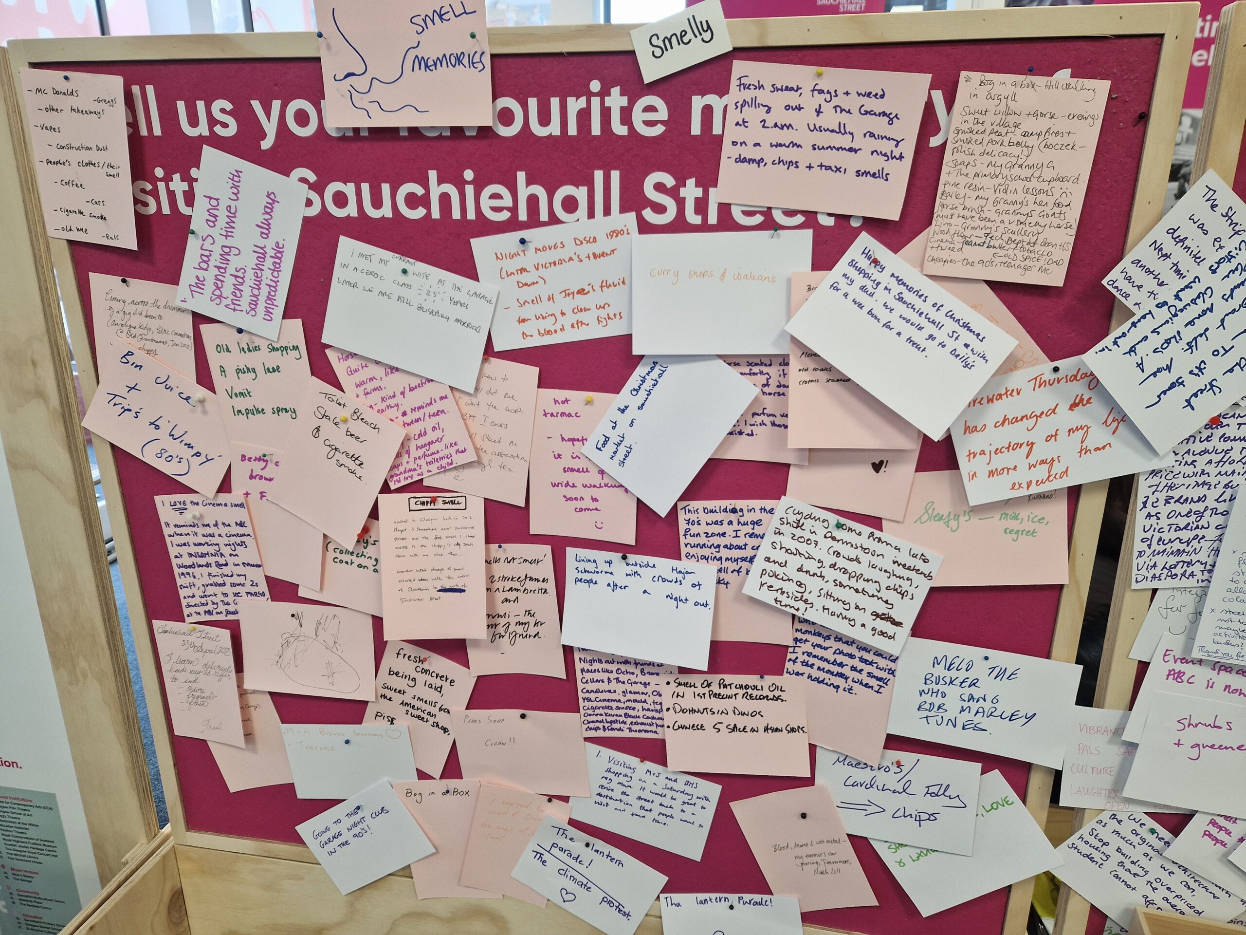 A pink noticeboard with lots of handwritten notes attached.