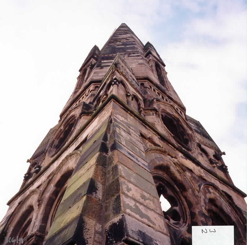 Looking up at a large stone built steeple.