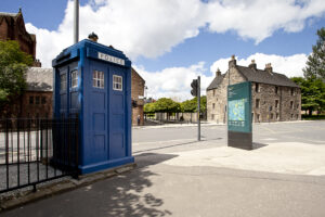 Blue police box on Castle Street on sunny day with the Provand's Lordship in the background.